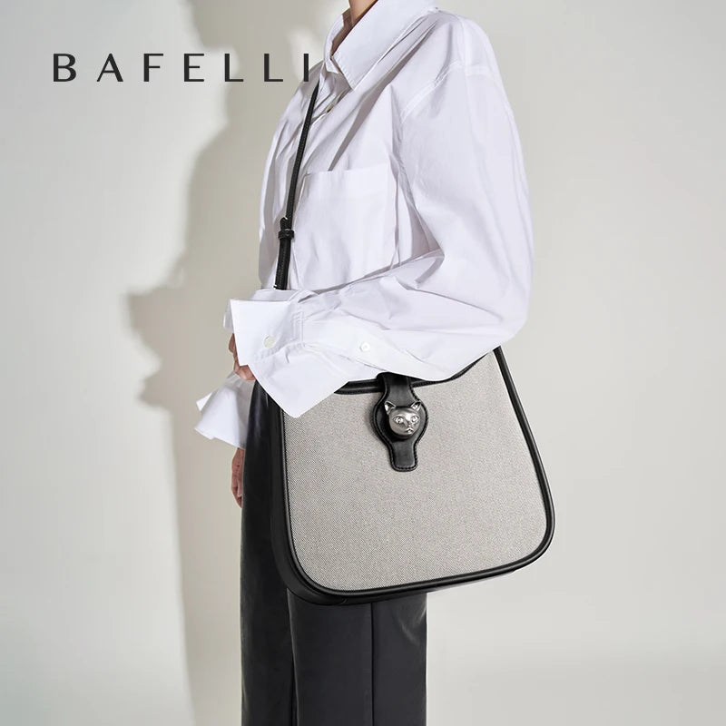 Beige Umhängetasche mit schwarzem Rand, verstellbarem Riemen und Metallanhänger.