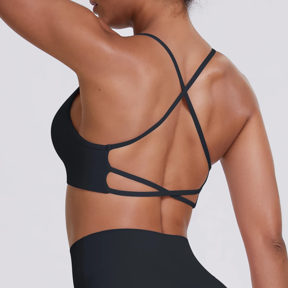 Schwarzes Sport-Crop-Top in Rückansicht, gekreuzte Träger mit Einschnitt-Design