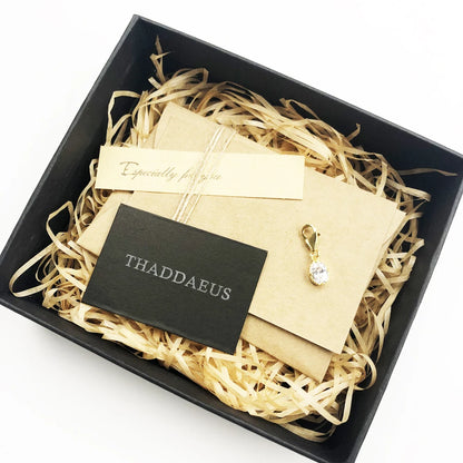 Ovaler Anhänger mit hellem Stein in goldfarbener Fassung auf Präsent-Box