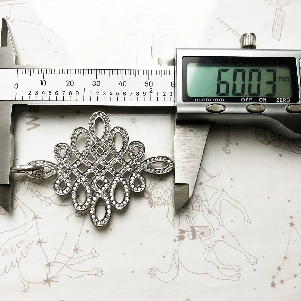 Silberner Anhänger Love-Knoten im Detail, mit Glitzerbesatz und strukturierten Ornamenten