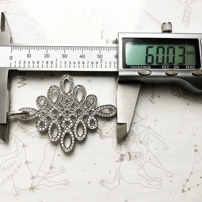 Silberner Anhänger Love-Knoten im Detail, mit Glitzerbesatz und strukturierten Ornamenten