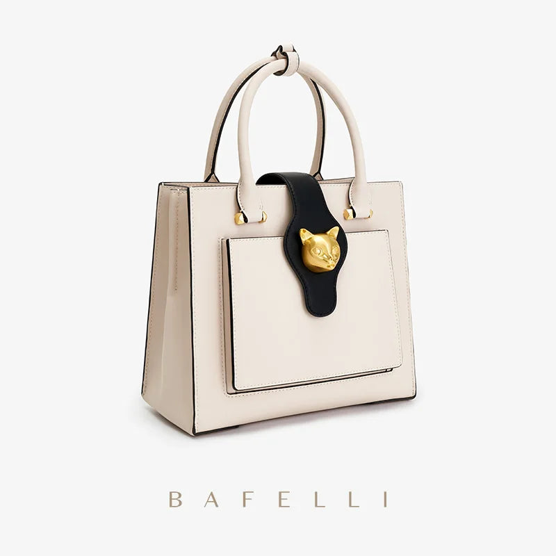 Beige Lederhandtasche mit Form, goldfarbener Katzenkopf-Applikation, Fronttasche und seitlichen Nähten
