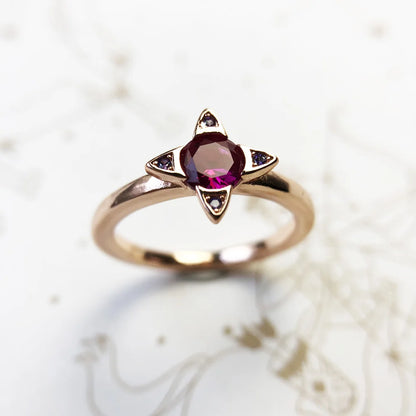 Ring mit violettem ovalen Stein in roségoldfarbener Fassung und vier Eck-Ziersteinen