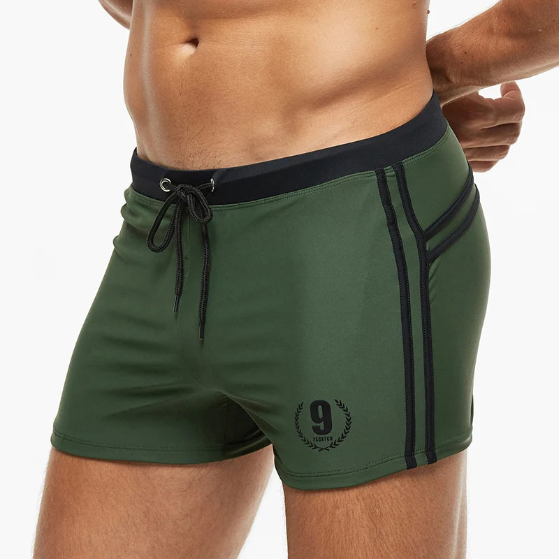 Kurze Herren-Badeshorts in Olivgrün mit schwarzen Seitenstreifen und Kordel