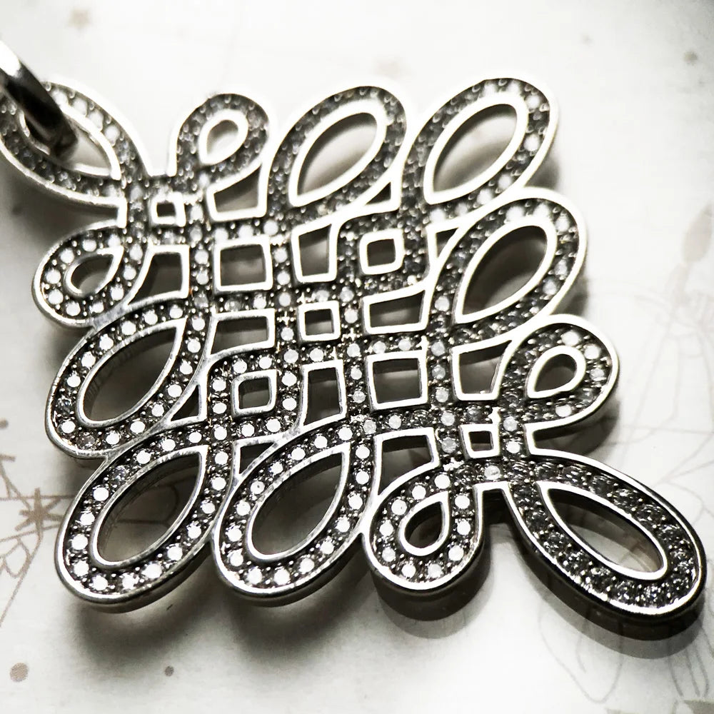Nahaufnahme Anhänger Love-Knoten, ovales Ornament mit dunklen Steinen und Glanzrand