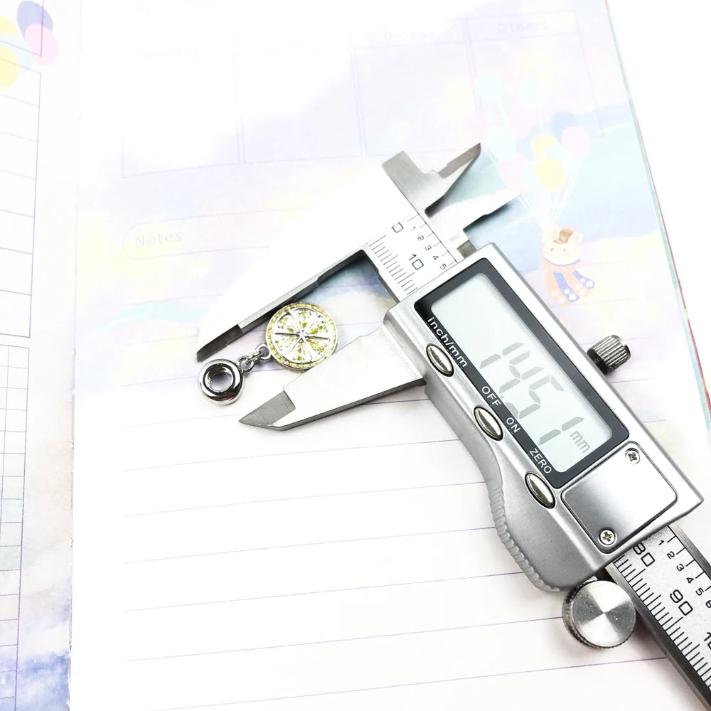 Zitronen-Charm aus 925 Sterlingsilber neben Messschieber, rundes Medaillon mit gelbem Stein
