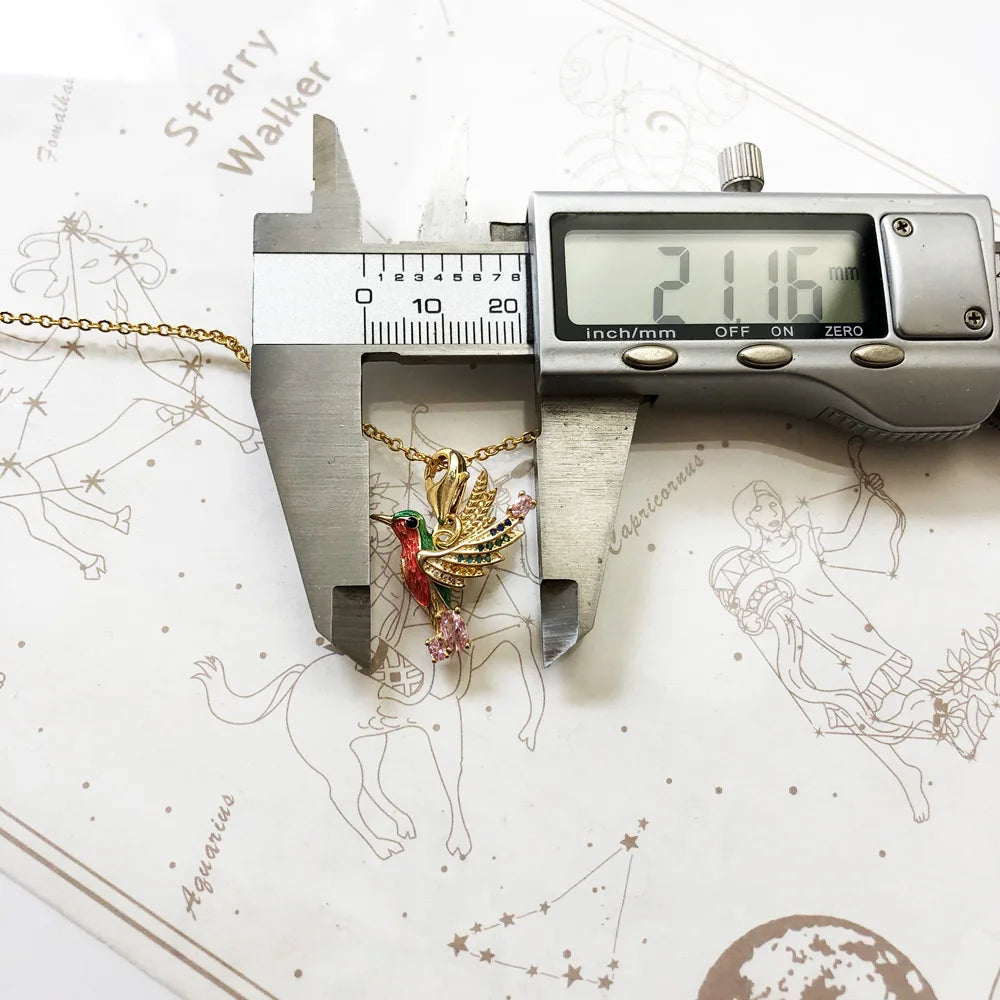 Kolibri-Anhänger an goldfarbener Halskette, mit Schieblehre vermessen