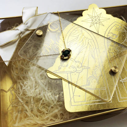 Halskette mit goldfarbener Kette und grünem ovalem Anhänger auf Accessoire-Box