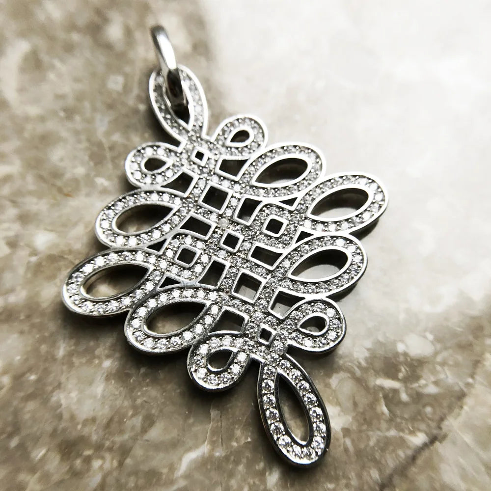 Nahaufnahme: Silberner Anhänger Love-Knoten mit Glitzersteinen, längliches Ornament-Design