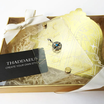 Kompass-Anhänger mit blauem Stein in goldfarbener Geschenkbox mit Schleife