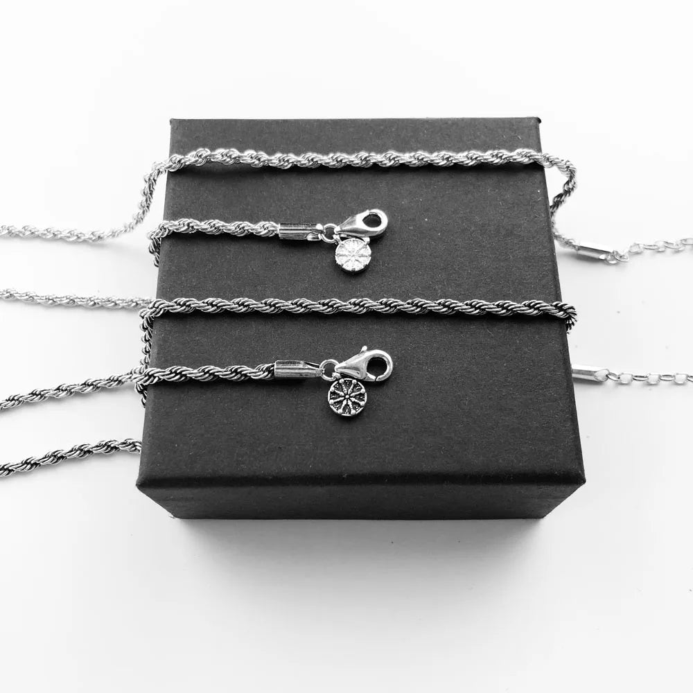 Mehrere silberne Drahtseilkette mit Rad-Charms und kleinen Anhängern auf Box
