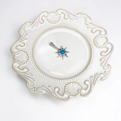 Sonnen-Anhänger aus 925-Sterlingsilber mit blauem Cabochon-Stein, auf Schmuckschale