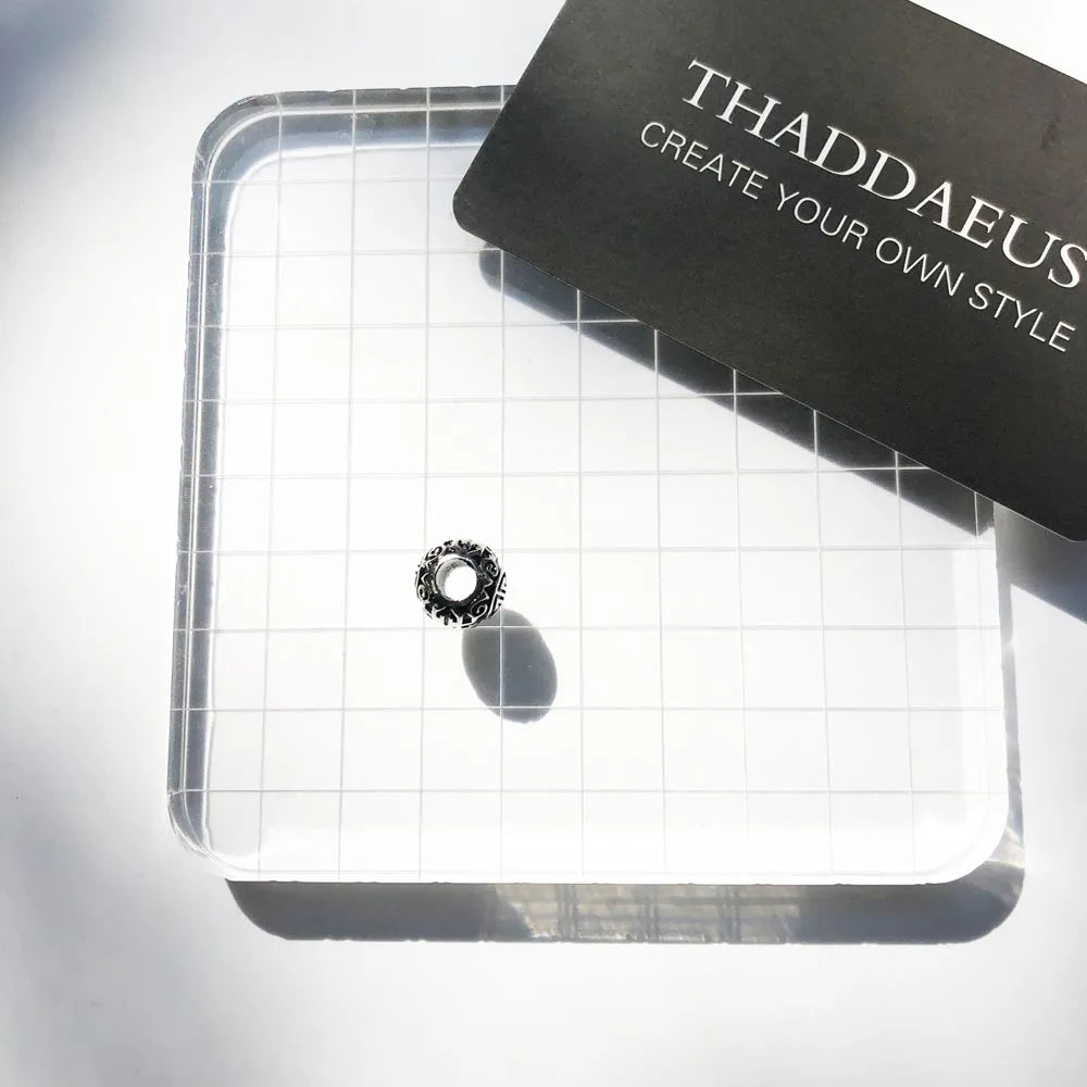 Silberner Charm auf Schmuckkarte, rundes Ornament mit eingefasstem Muster