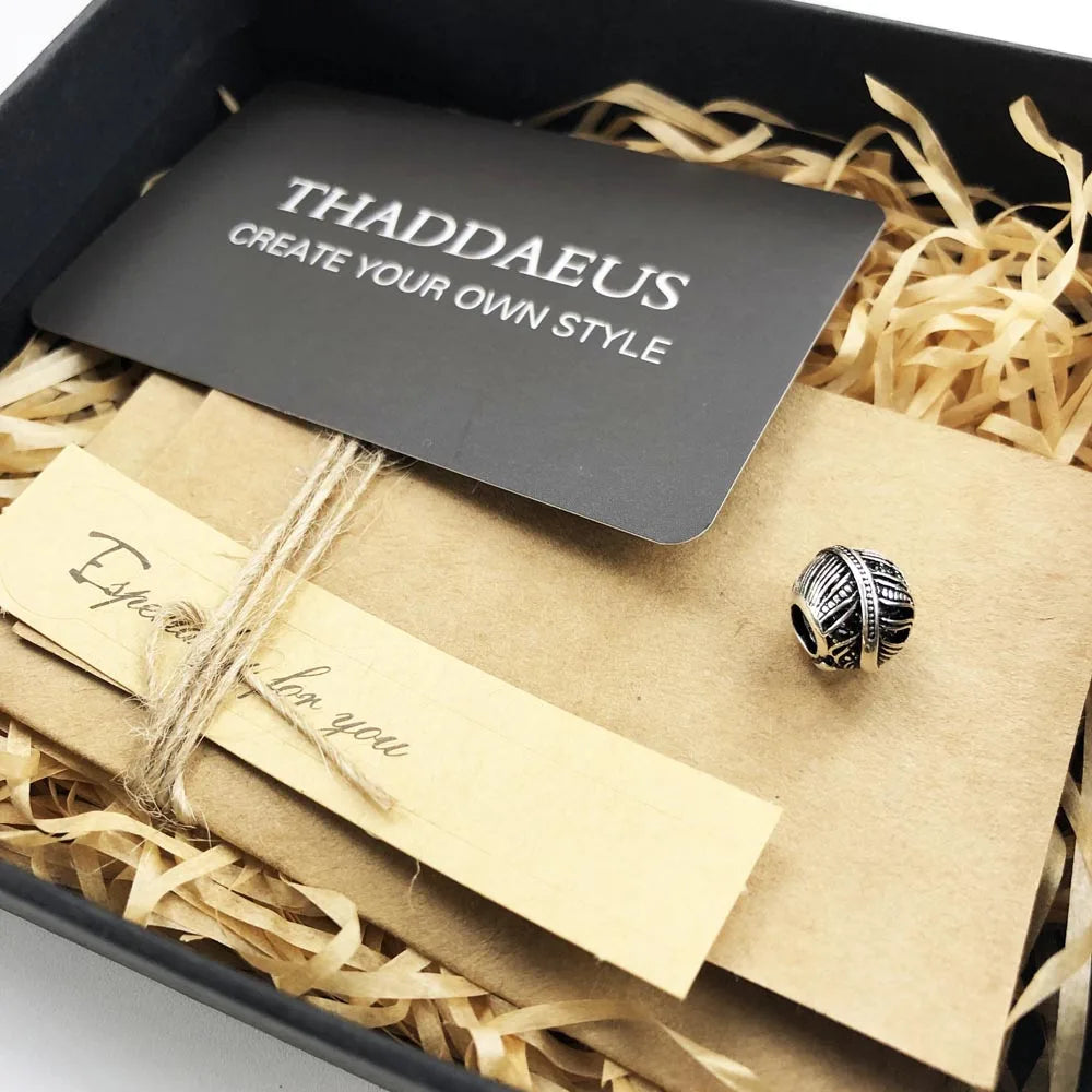 Silberner Feder-Charm mit schwarzem Relief in Geschenkbox mit Füllmaterial