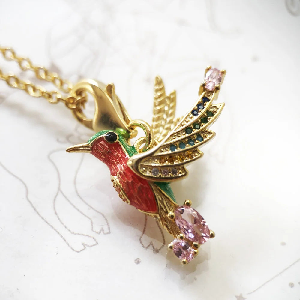 Detailansicht: Kolibri-Anhänger an goldfarbener Halskette mit farbigen Steinen