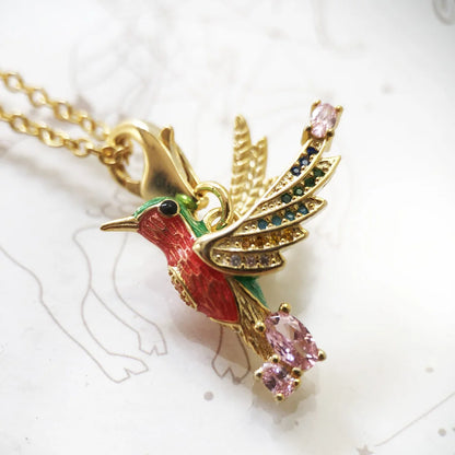 Detailansicht: Kolibri-Anhänger an goldfarbener Halskette mit farbigen Steinen