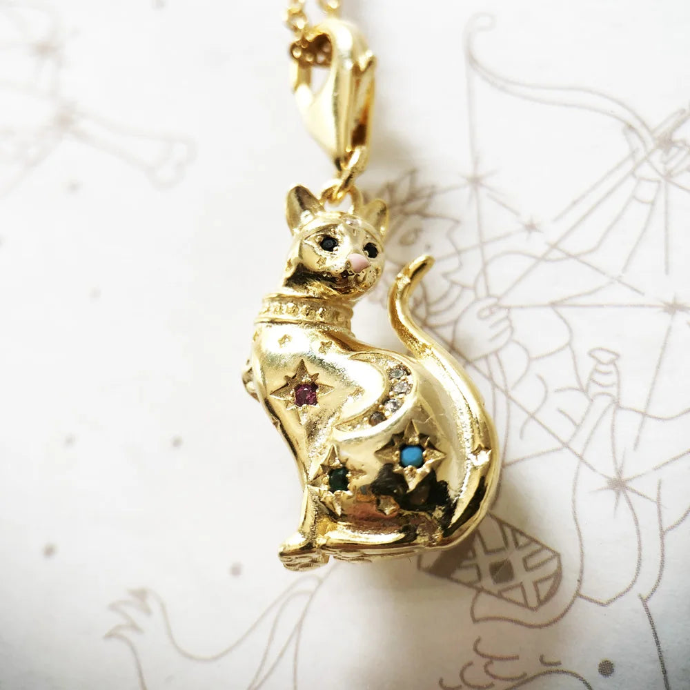 Nahaufnahme goldener Katzenanhänger mit bunten Schmucksteinen, an goldfarbener Kette