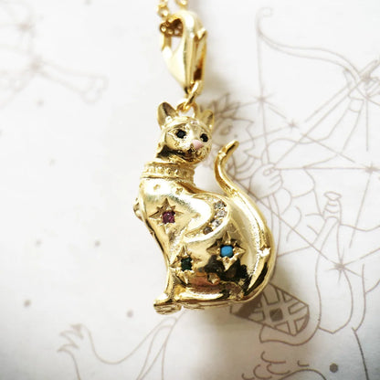 Nahaufnahme goldener Katzenanhänger mit bunten Schmucksteinen, an goldfarbener Kette