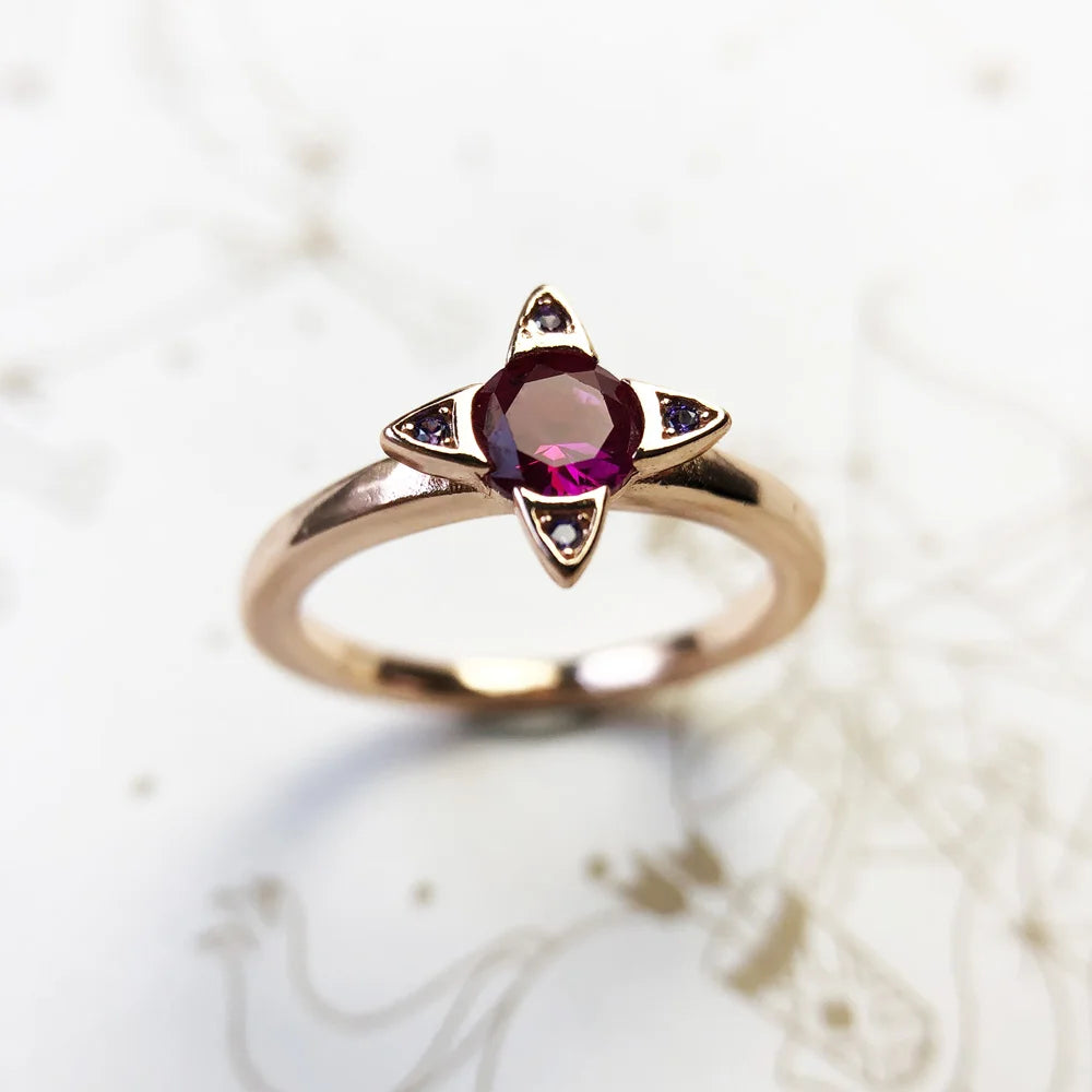 Frontansicht: roségoldfarbener Ring mit violettem Stein und Ziersteinen
