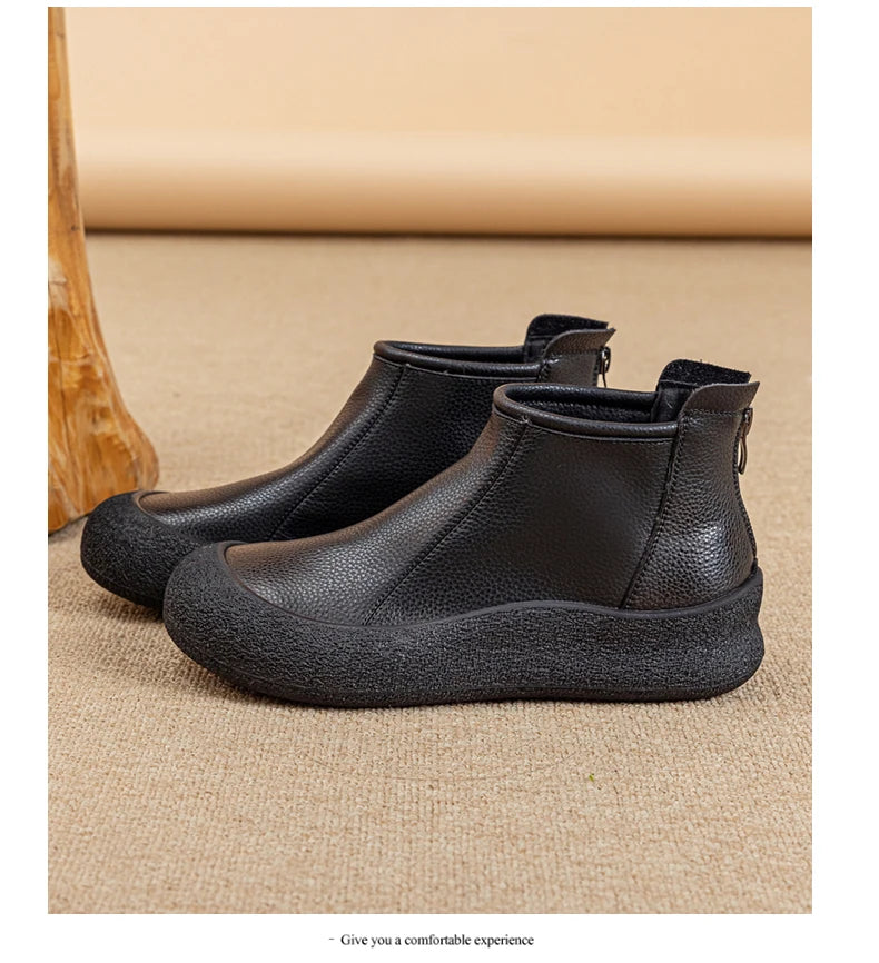 Schwarze flache Leder-Stiefeletten mit Rundkappe und seitlichem Reißverschluss.