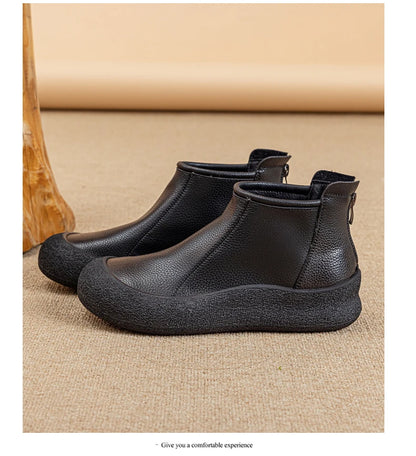 Schwarze flache Leder-Stiefeletten mit Rundkappe und seitlichem Reißverschluss.