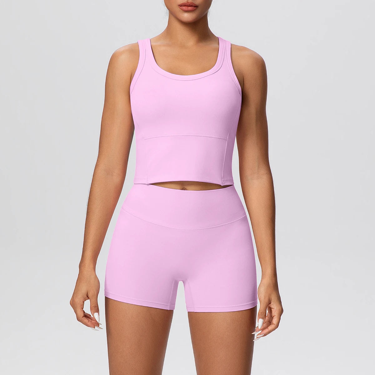 Damen-Yoga-Set in Rosa: ärmelloses Croptop und kurze Leggings mit Midriff-Ausschnitt.