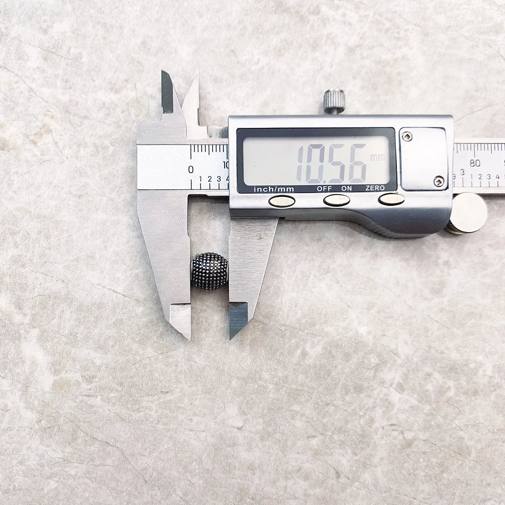 Kathmandu Charm-Perle aus 925er Sterlingsilber neben Messschieber, rundes Noppenmuster
