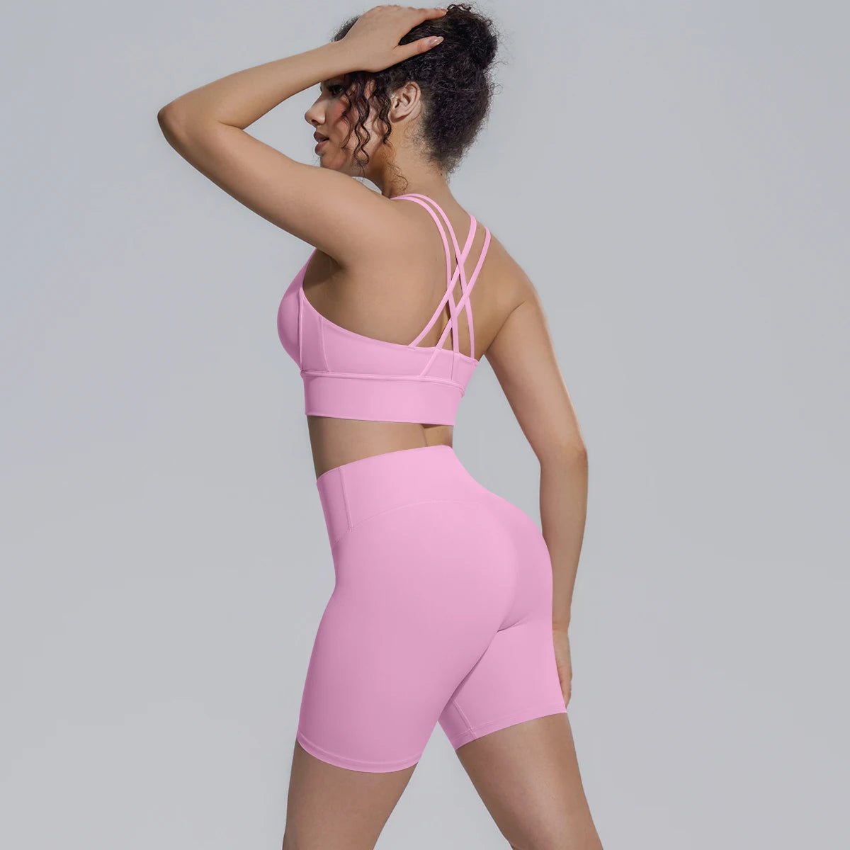 Rosa Yoga-Set von hinten: Sporttop mit gekreuzten Trägern über Shorts