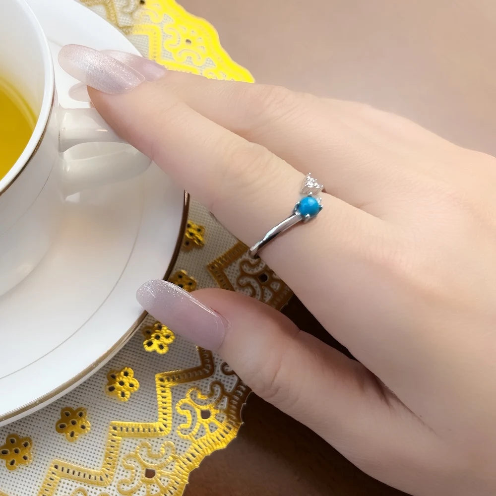 Ring am Handgelenk: silbernes Band mit türkisblauem Stein und Zirkonia