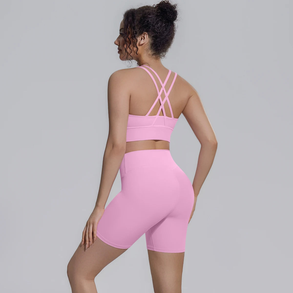 Rosa Yoga-Set von hinten: gekreuzte Träger am Sporttop über Shorts