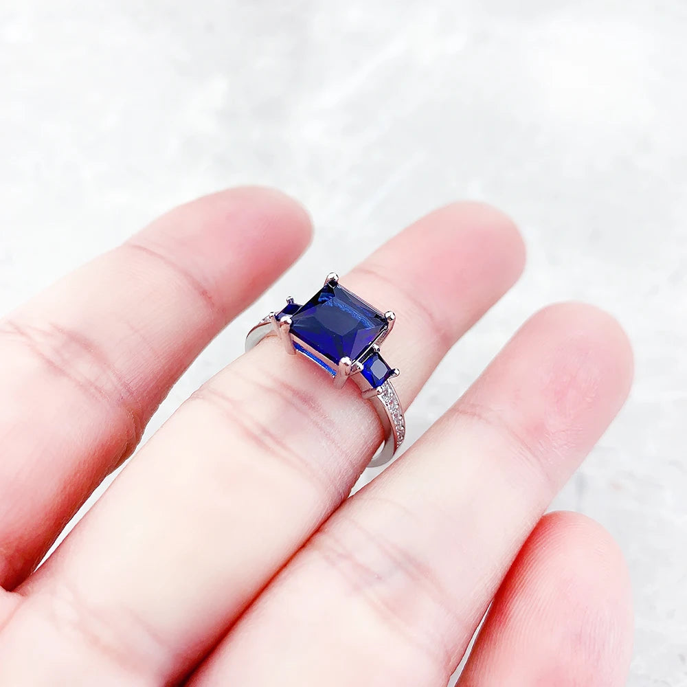Silberner Ring mit quadratischem blauem Stein in der Hand, Detail der Fassung