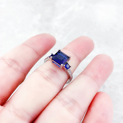 Silberner Ring mit quadratischem blauem Stein in der Hand, Detail der Fassung