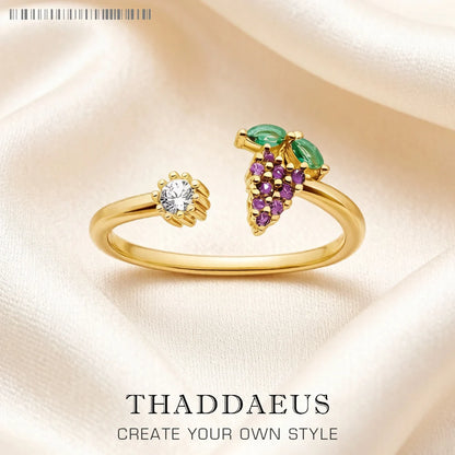 Goldfarbener Ring mit ovalem Grünstein und violetten Traubensteinen sowie hellem Zirkon