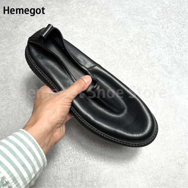 Schwarzer Leder-Loafer, Hand hält den Schlupfkragen, flache Sohle