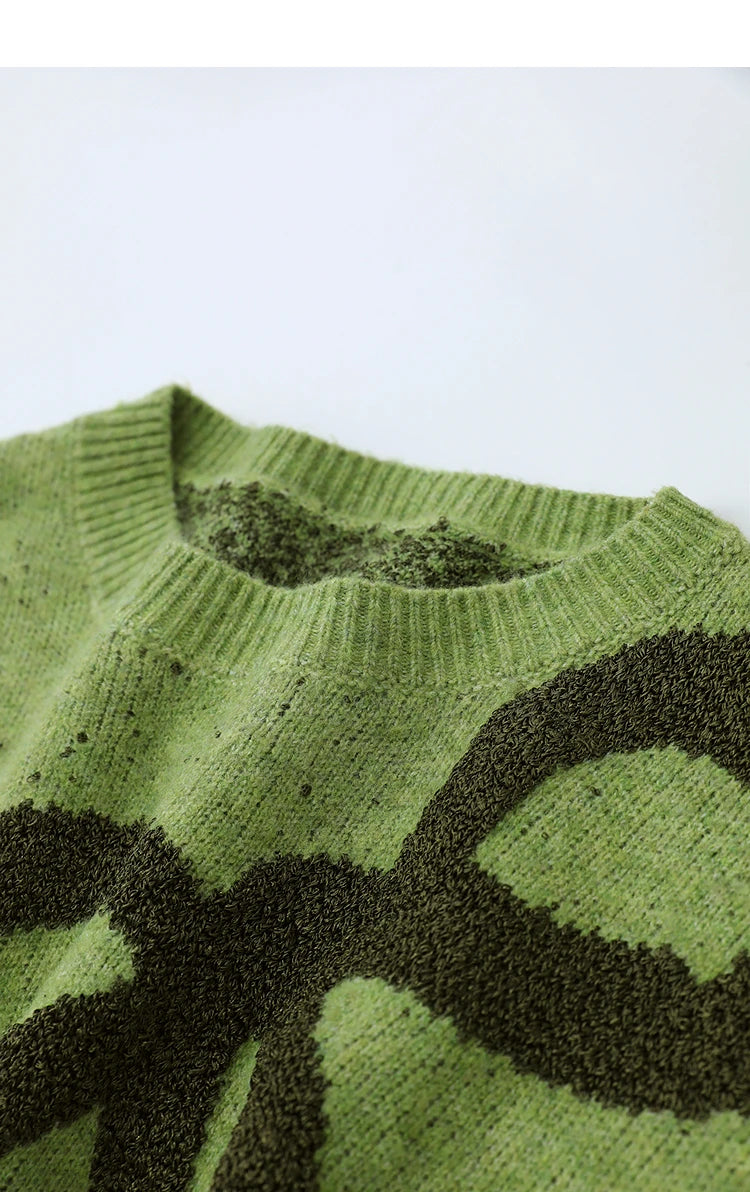 Nahaufnahme: grüner Jacquardpullover mit schwarzem Muster am Halsausschnitt