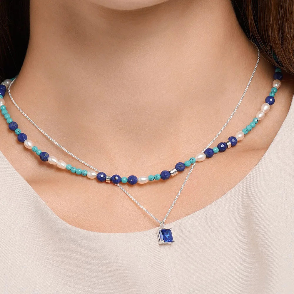 Mehrreihige Halskette mit blauen Perlen und blauem quadratischem Anhänger am Hals