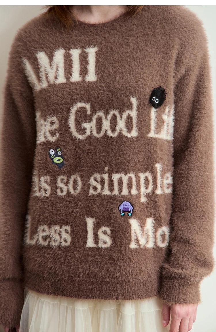 Camelfarbener Damenpullover im Detail: großer Schriftzug und kleine Motiv-Patches