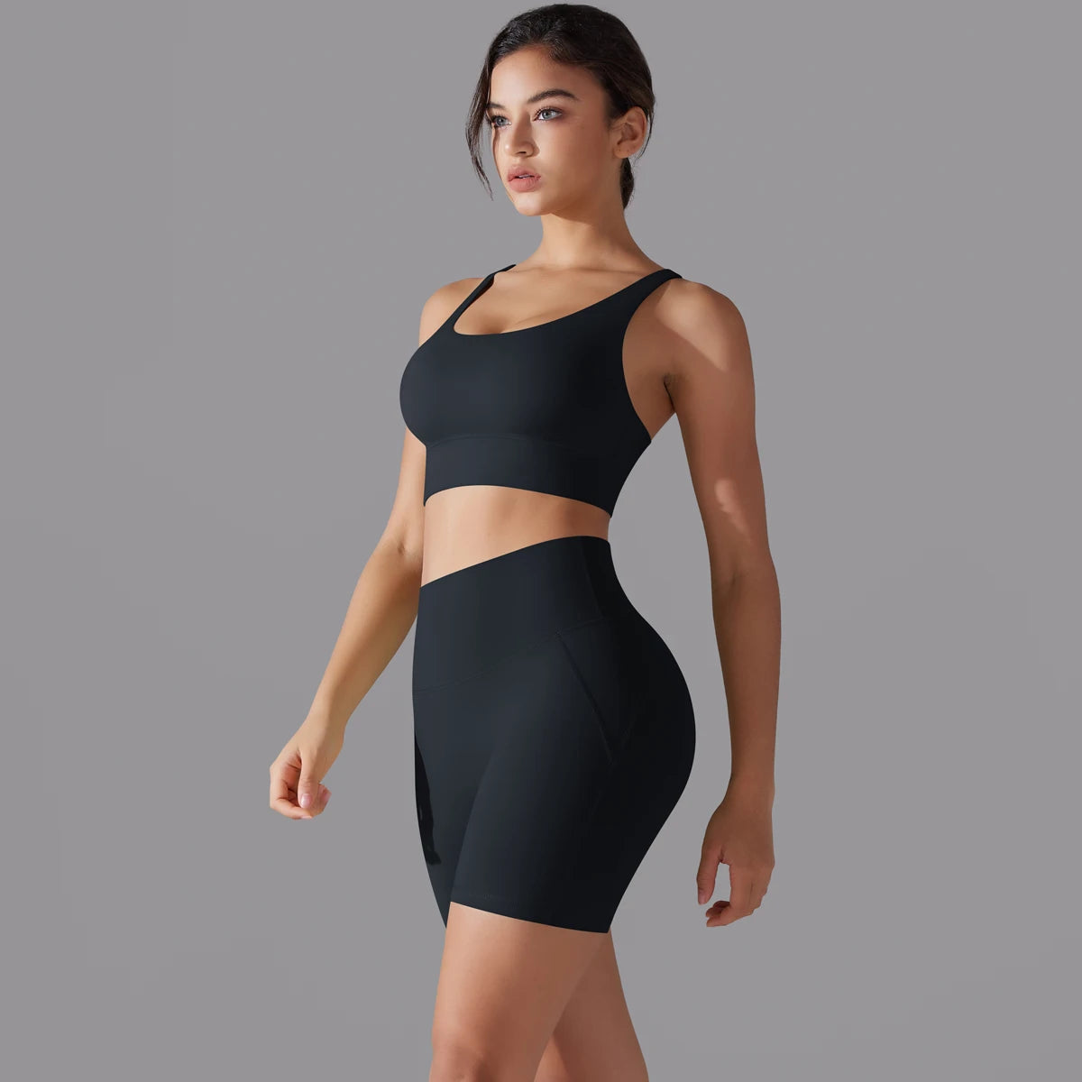 Nahtloses Fitnessset für Damen: schwarzes Sporttop und kurze Leggings im Set-Look