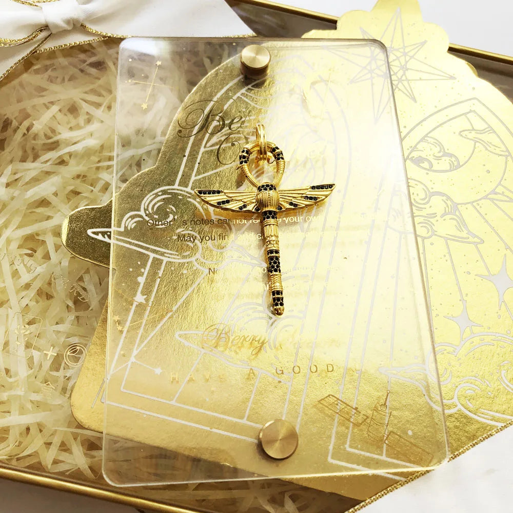 Schmuckanhänger in Klarsichtverpackung, goldfarbenes Ankh-Kreuz mit Flügeln