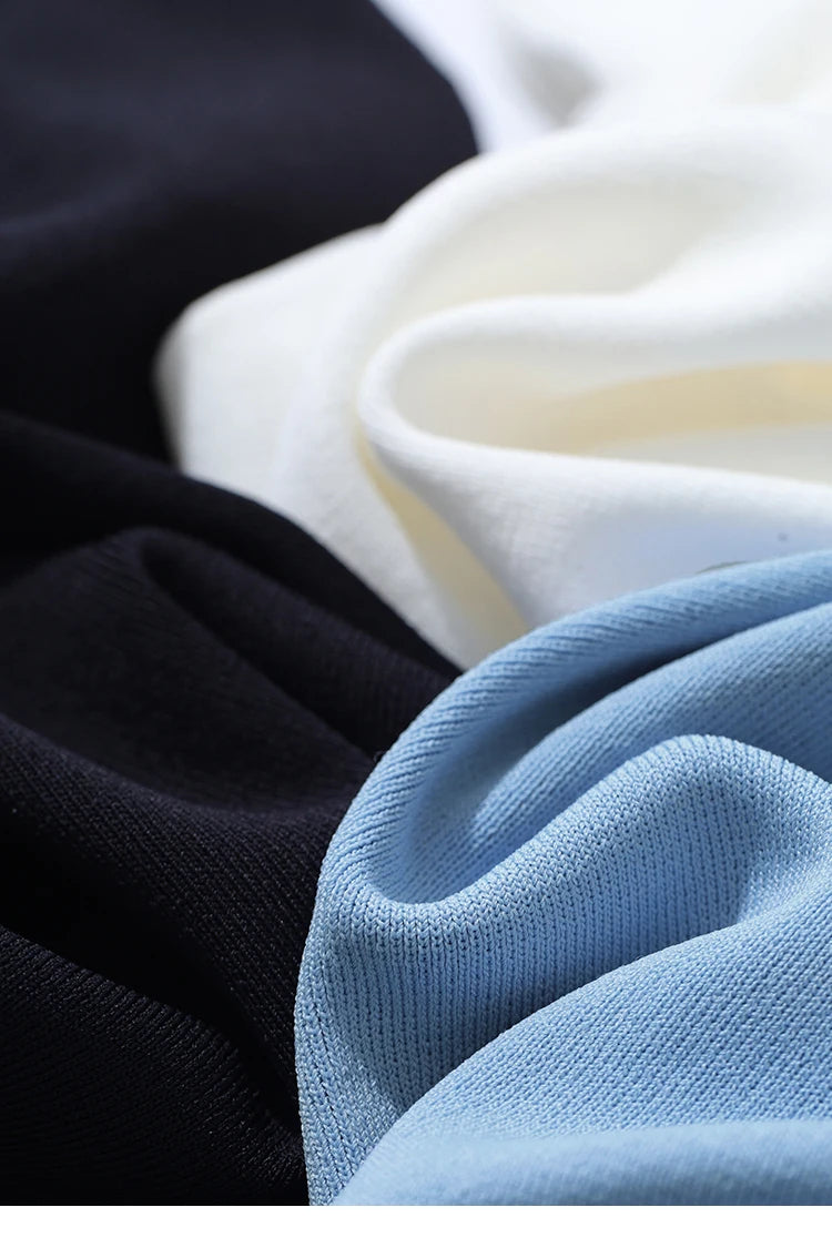 Mehrere Farben im Vergleich: hellblaues Stricktop neben schwarzem und beigem Stoff