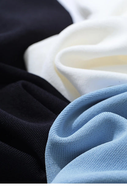 Mehrere Farben im Vergleich: hellblaues Stricktop neben schwarzem und beigem Stoff