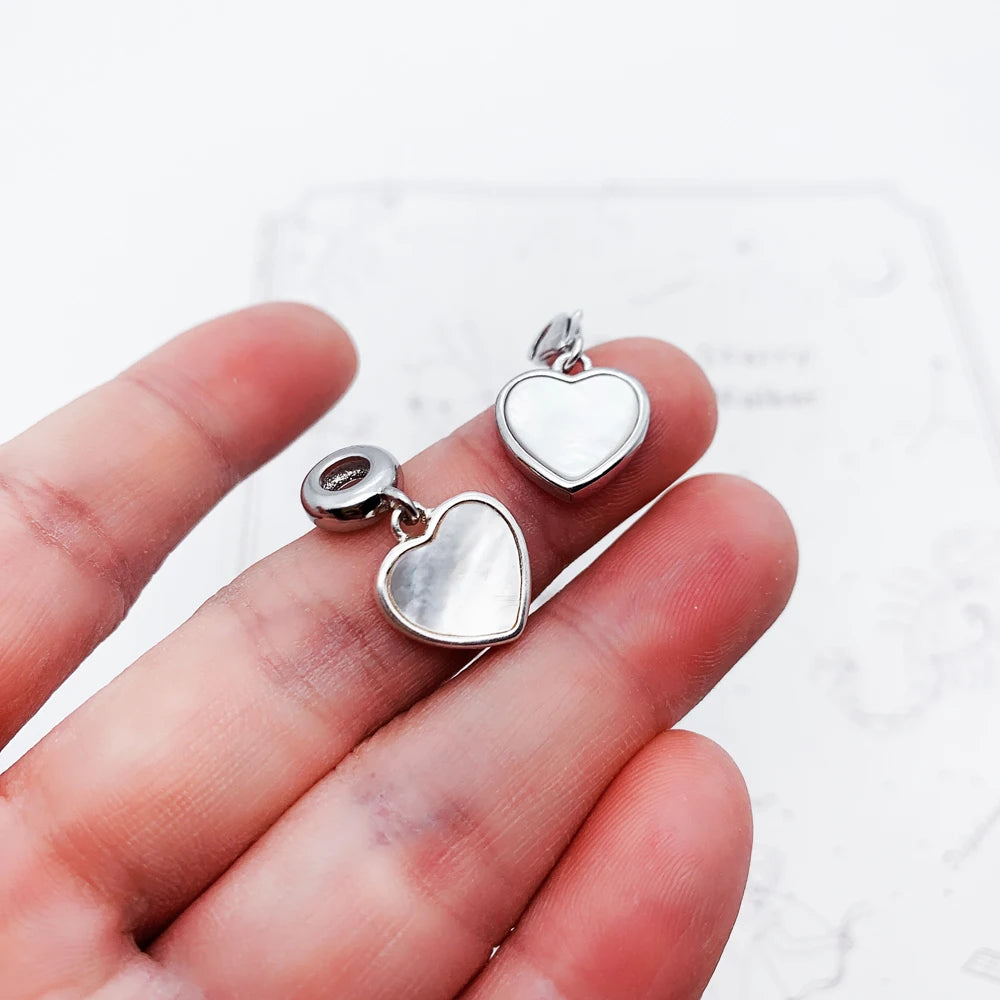 Zwei herzförmige Anhänger aus 925 Sterlingsilber in der Hand, mit Öse