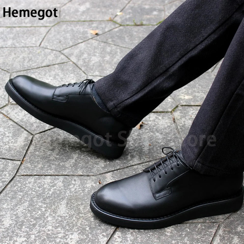 Schwarze Schnürschuhe für Herren, seitliche Ansicht neben Hose auf Steinpflaster