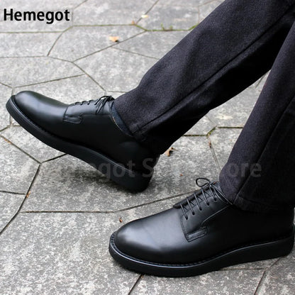 Schwarze Schnürschuhe für Herren, seitliche Ansicht neben Hose auf Steinpflaster