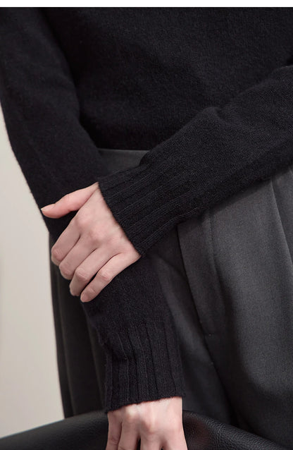 Nahaufnahme: Dunkler Strickpullover mit gerippten Bündchen und weißem Unterteil am Saum.