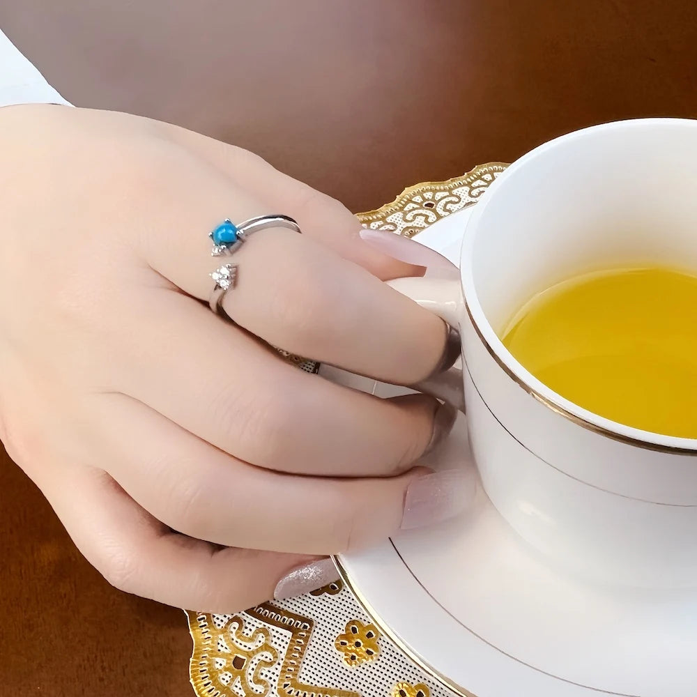 Silberner Ring mit türkisblauem Stein auf der Hand, verziert mit Zirkonia