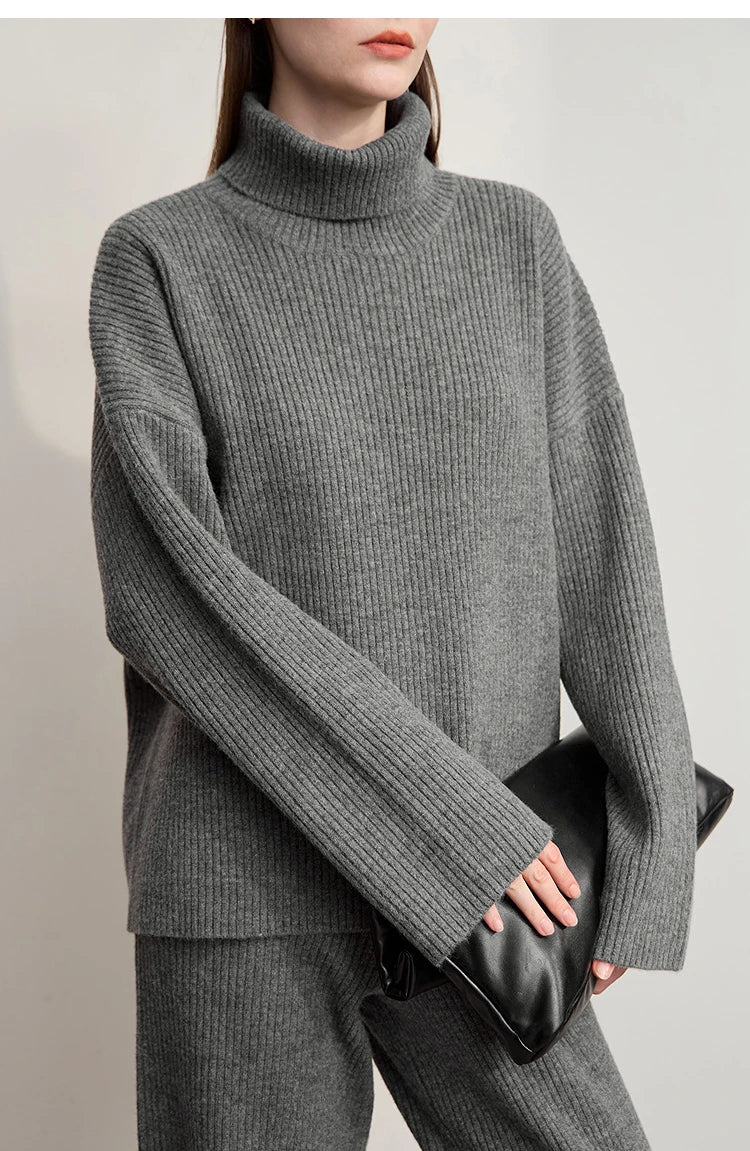 Grauer Rollkragenpullover mit langen Ärmeln, dazu graue weite Hose