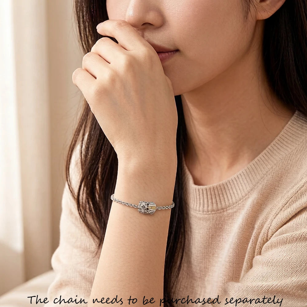Armband mit silbernem Charm am Handgelenk, Ritterhelm-Motiv mit Goldakzenten