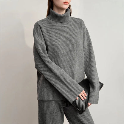 Dunkelgrauer Rollkragenpullover im Rippenstrick-Look, lange Ärmel; schwarze Umhängetasche