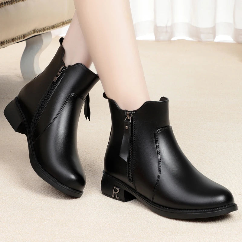 Schwarze Stiefelette am Fuß mit Reißverschluss, Blockabsatz und glatter Oberfläche.